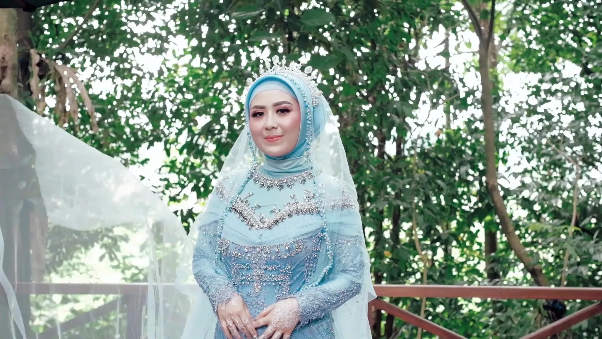 Pengantin wanita berbusana biru muda di teras taman