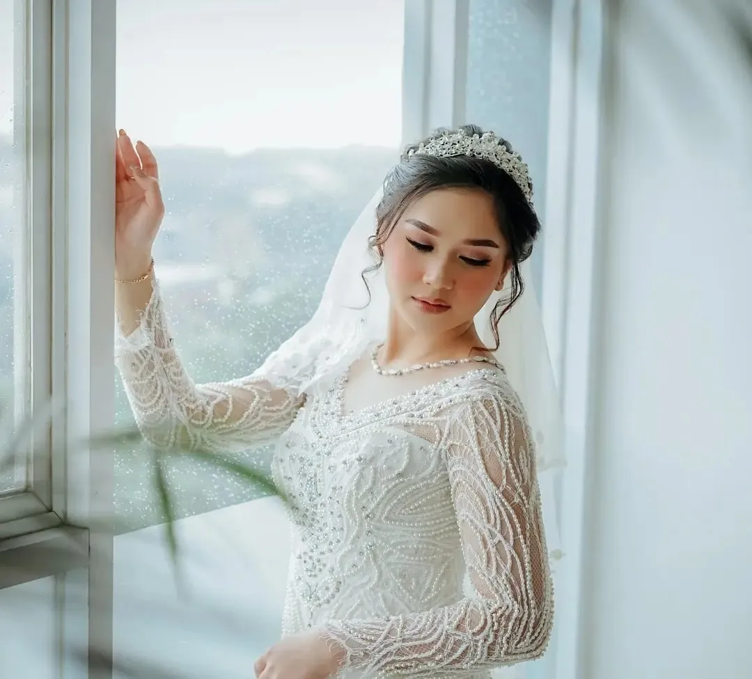 Pengantin wanita bergaun putih di dekat jendela