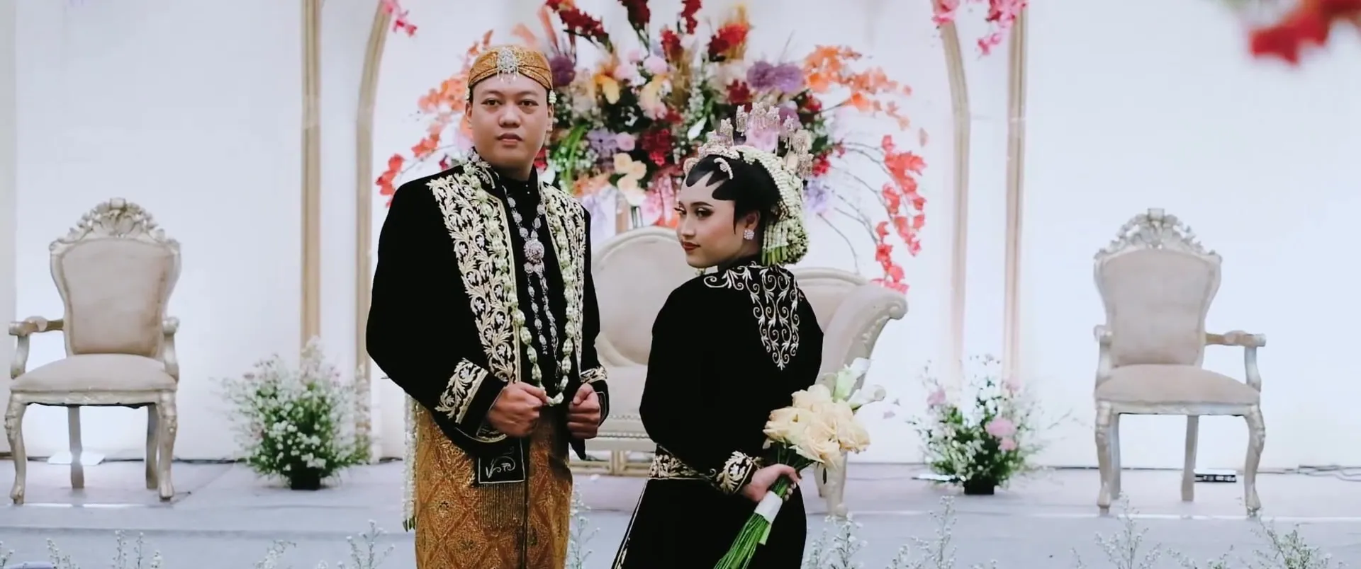 Pasangan pengantin adat Jawa berdiri di pelaminan