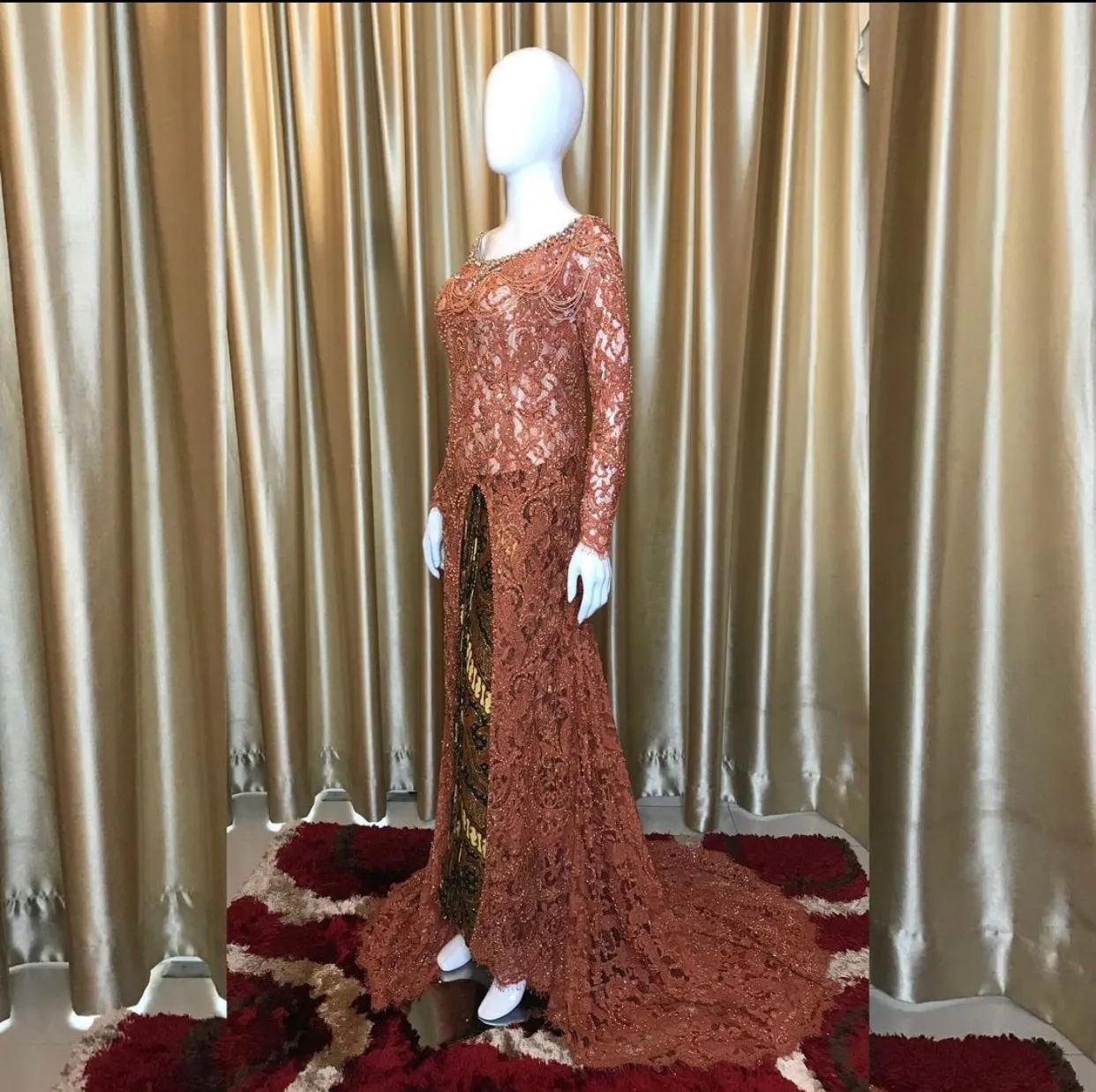 Kebaya brokat berwarna bata dipajang di manekin
