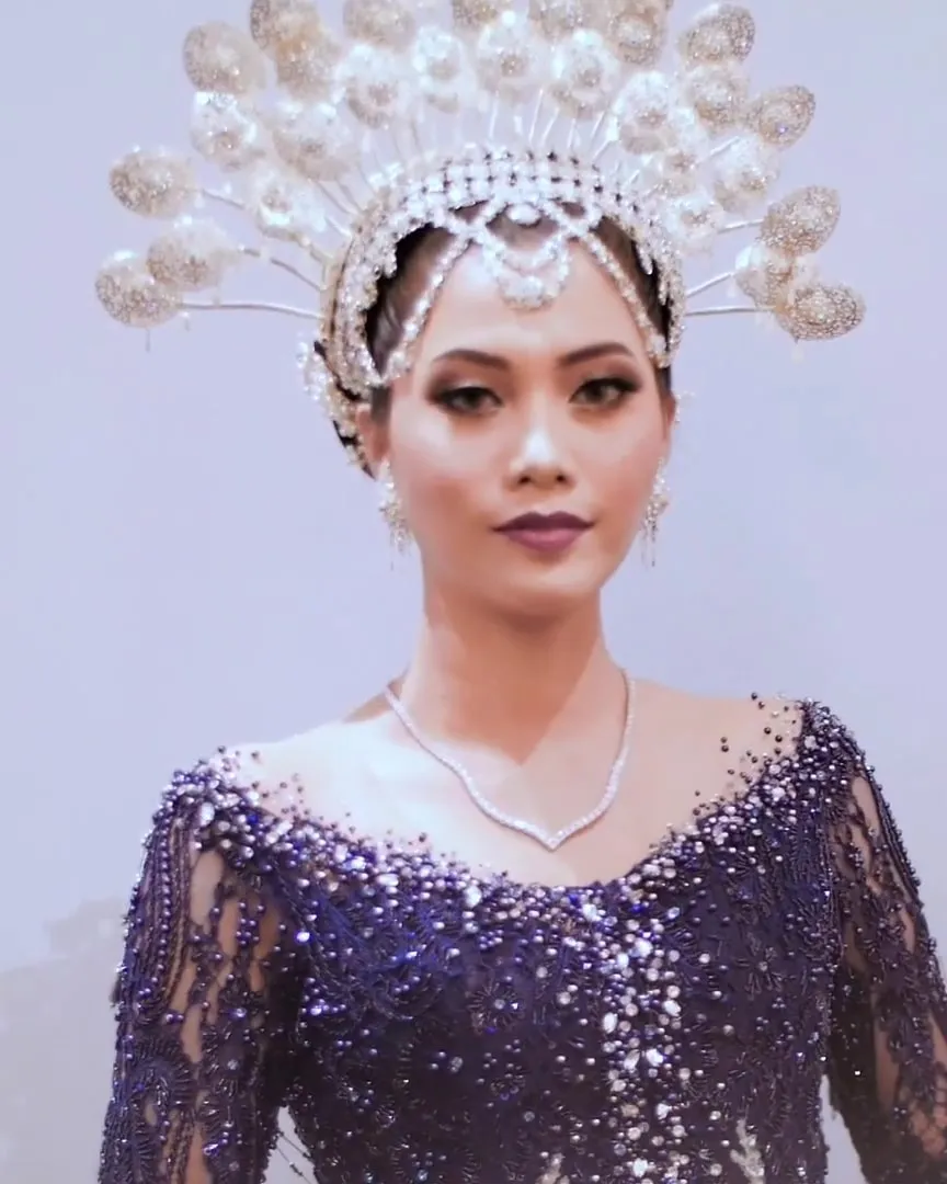 Model mengenakan kebaya payet biru tua dengan mahkota putih