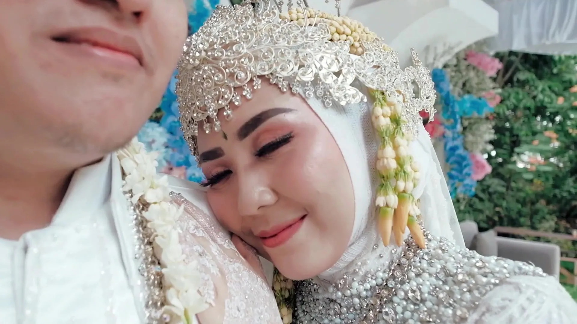 Pengantin wanita bersiger tersenyum di pelukan pengantin pria